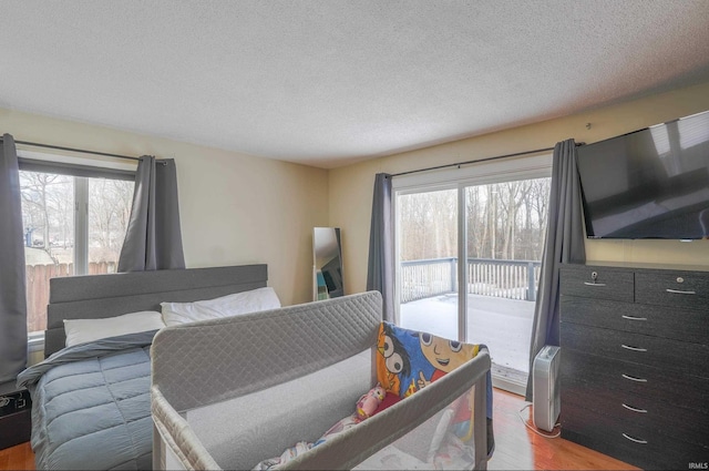 bedroom with light wood-type flooring, a textured ceiling, and access to outside