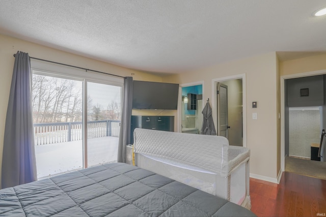 bedroom featuring dark hardwood / wood-style flooring, ensuite bath, access to outside, and a textured ceiling