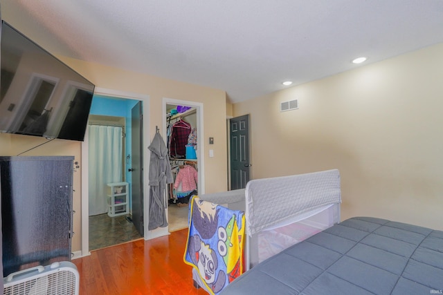 bedroom with hardwood / wood-style floors, a spacious closet, and a closet