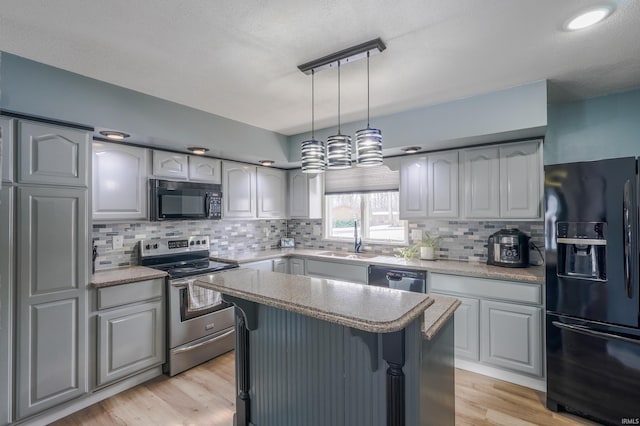 kitchen featuring pendant lighting, sink, gray cabinetry, a center island, and black appliances