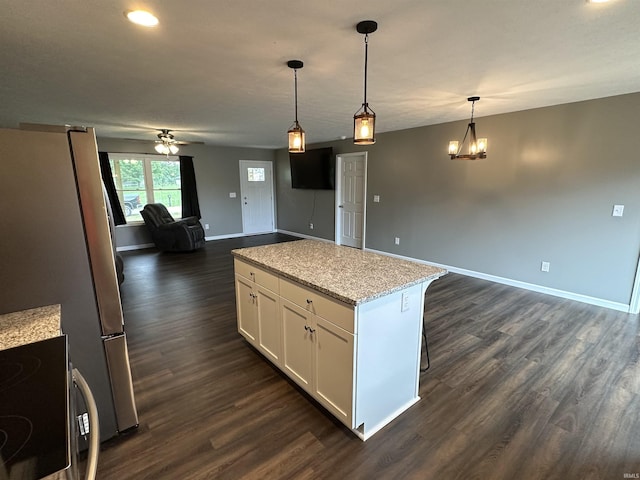 kitchen with dark wood-type flooring, light stone counters, decorative light fixtures, white cabinets, and ceiling fan with notable chandelier