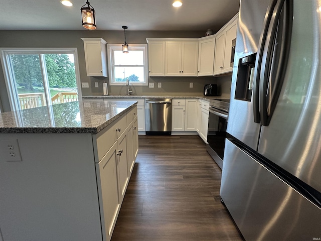 kitchen featuring white cabinets, stainless steel appliances, light stone counters, and hanging light fixtures