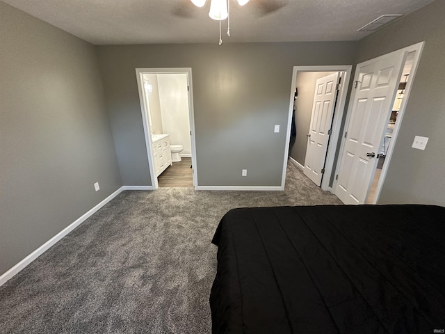 unfurnished bedroom with ensuite bath, ceiling fan, a textured ceiling, and dark colored carpet