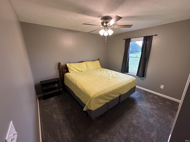 bedroom with ceiling fan, dark carpet, and a textured ceiling