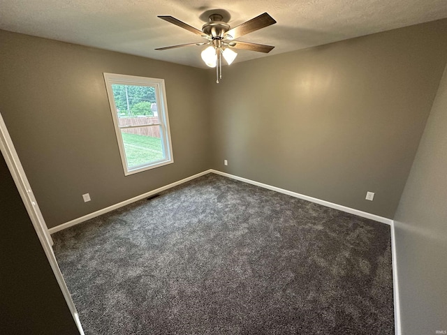 unfurnished room with ceiling fan, dark carpet, and a textured ceiling