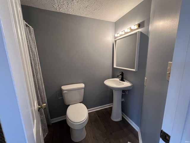 bathroom with sink, toilet, wood-type flooring, and a textured ceiling