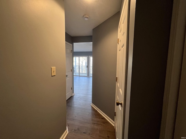 hallway with a textured ceiling and dark hardwood / wood-style floors