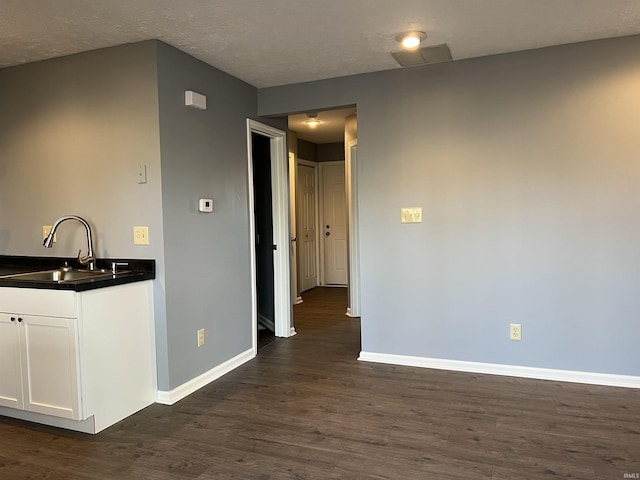 kitchen with white cabinets, a textured ceiling, sink, and dark wood-type flooring