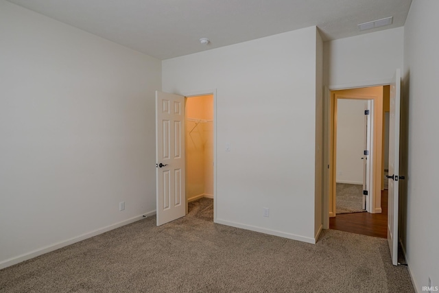 unfurnished bedroom with a walk in closet, a closet, and carpet floors