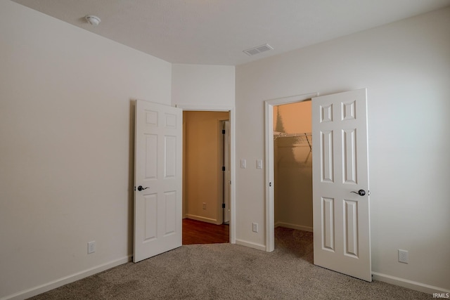 unfurnished bedroom featuring carpet, a spacious closet, and a closet