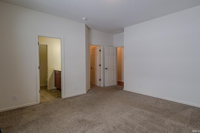 unfurnished bedroom with ensuite bathroom, light colored carpet, and a spacious closet