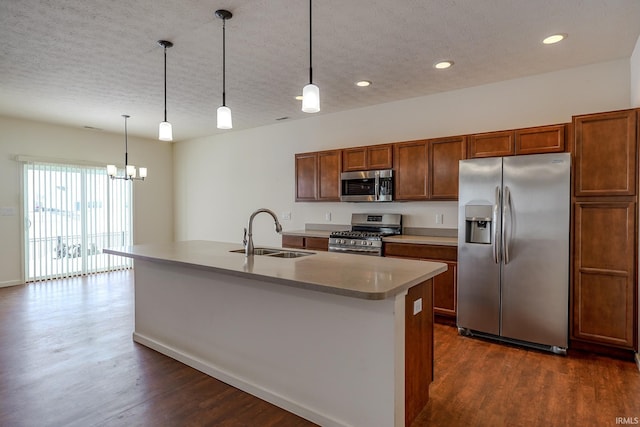 kitchen featuring stainless steel appliances, a kitchen island with sink, sink, pendant lighting, and an inviting chandelier