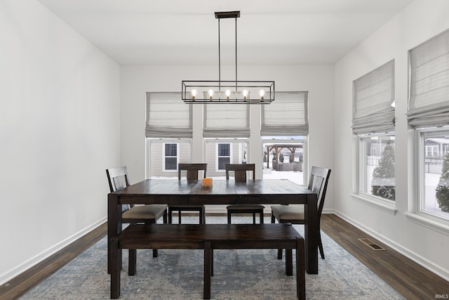 dining area featuring a chandelier, dark wood-style flooring, visible vents, and baseboards