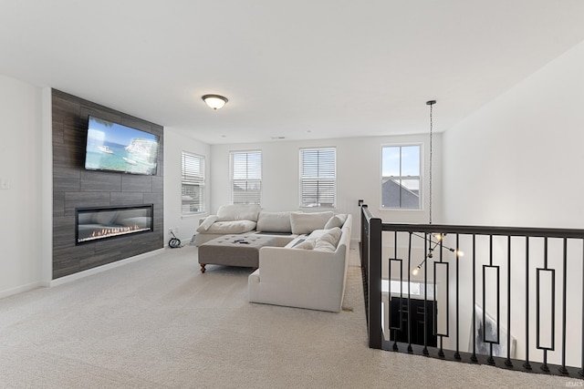 living room featuring an inviting chandelier, carpet, a fireplace, and baseboards