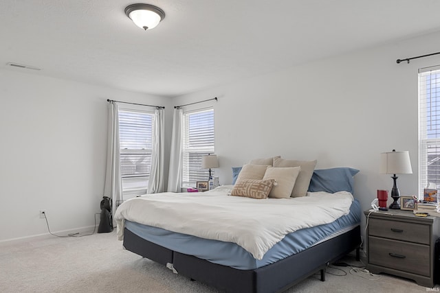 carpeted bedroom featuring visible vents, baseboards, and multiple windows