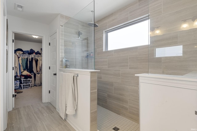 bathroom featuring a walk in shower, a spacious closet, and visible vents