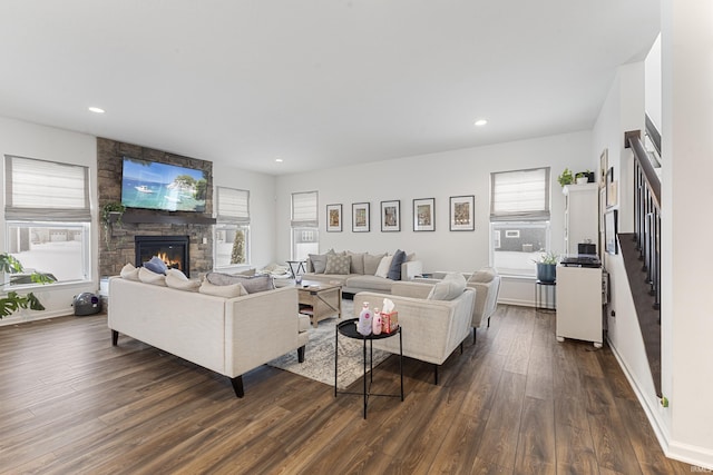 living room with a stone fireplace and dark hardwood / wood-style flooring