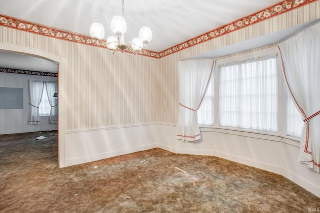 empty room featuring carpet flooring, a healthy amount of sunlight, and a notable chandelier