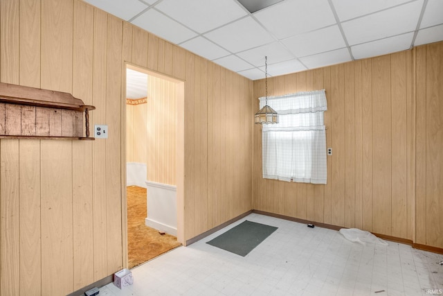 spare room with a paneled ceiling and wooden walls