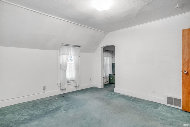 carpeted spare room featuring a textured ceiling and vaulted ceiling