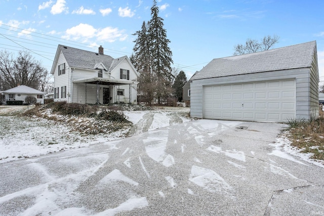 view of snowy exterior featuring an outbuilding and a garage