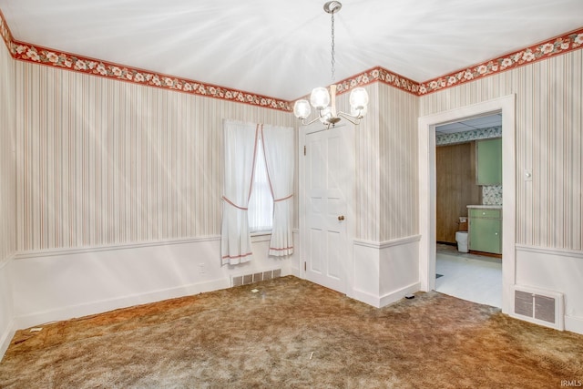 carpeted spare room with an inviting chandelier