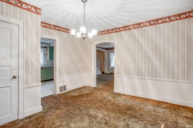 empty room featuring carpet flooring and an inviting chandelier