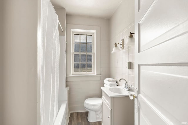 full bathroom with shower / bath combo, toilet, vanity, tile walls, and hardwood / wood-style flooring