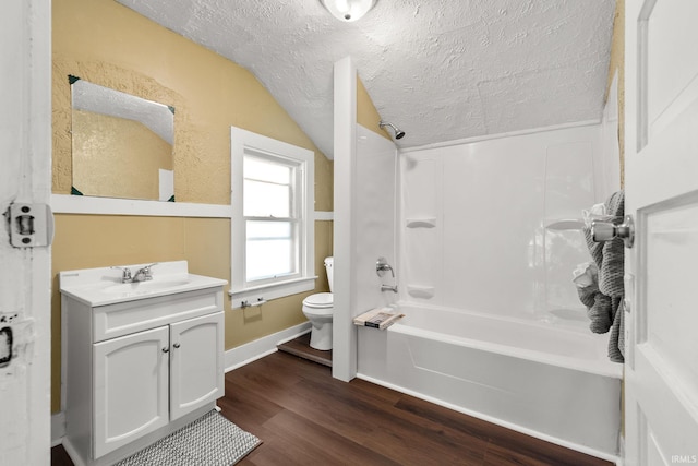 full bathroom featuring wood-type flooring, a textured ceiling, vaulted ceiling, shower / washtub combination, and vanity