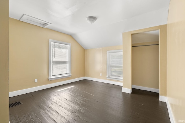 unfurnished bedroom featuring dark hardwood / wood-style floors, vaulted ceiling, and a closet