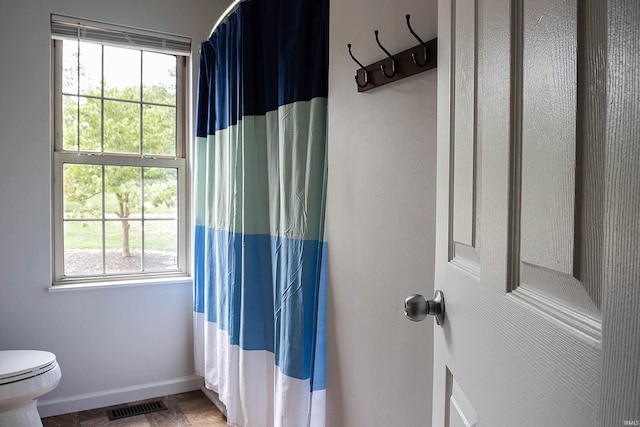 bathroom featuring walk in shower, a healthy amount of sunlight, and toilet