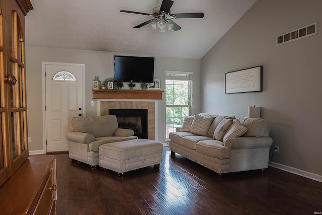 living room featuring ceiling fan, vaulted ceiling, dark wood-type flooring, and a tiled fireplace