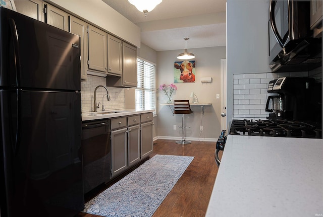 kitchen featuring decorative backsplash, sink, black appliances, decorative light fixtures, and dark hardwood / wood-style floors