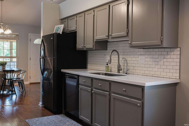 kitchen featuring sink, decorative light fixtures, black dishwasher, gray cabinets, and dark hardwood / wood-style floors