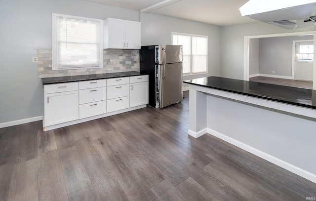 kitchen featuring white cabinets, backsplash, dark hardwood / wood-style floors, and stainless steel refrigerator