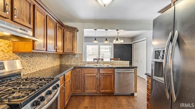 kitchen featuring ventilation hood, sink, decorative backsplash, appliances with stainless steel finishes, and decorative light fixtures