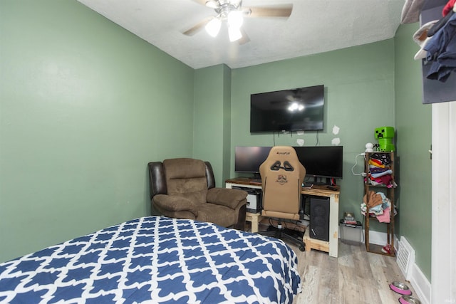 bedroom with ceiling fan, wood-type flooring, and a textured ceiling