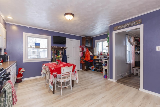 dining area with a textured ceiling, light hardwood / wood-style floors, and crown molding