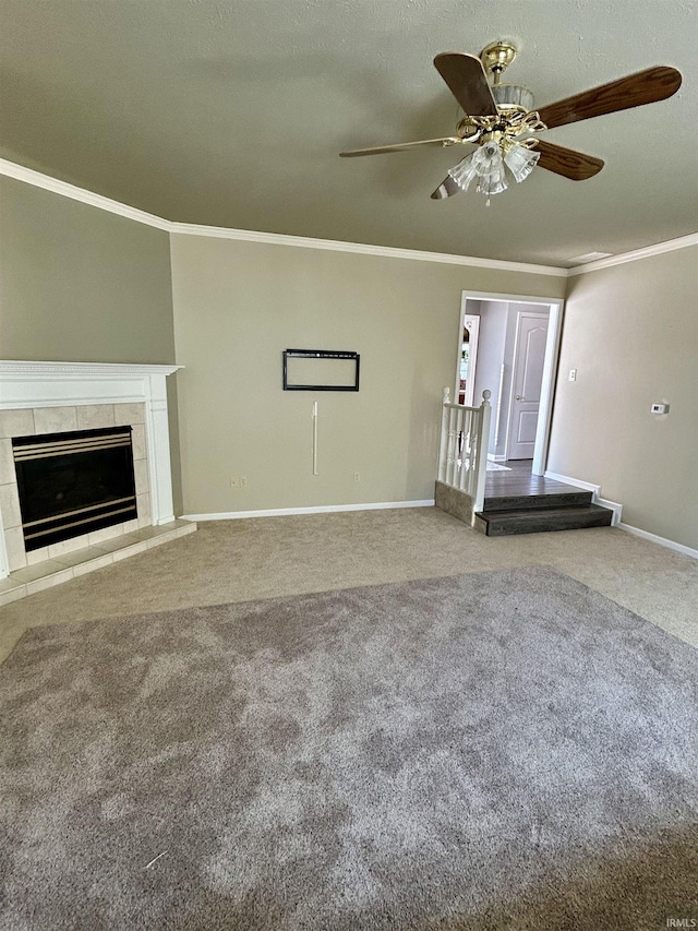 unfurnished living room featuring a tile fireplace, carpet flooring, a ceiling fan, baseboards, and ornamental molding