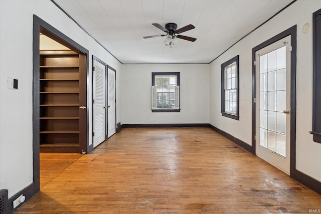 unfurnished room with built in shelves, french doors, light hardwood / wood-style floors, and ceiling fan