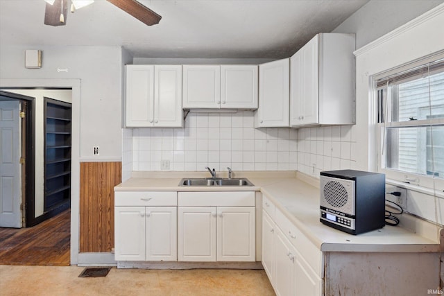 kitchen with decorative backsplash, white cabinetry, ceiling fan, and sink