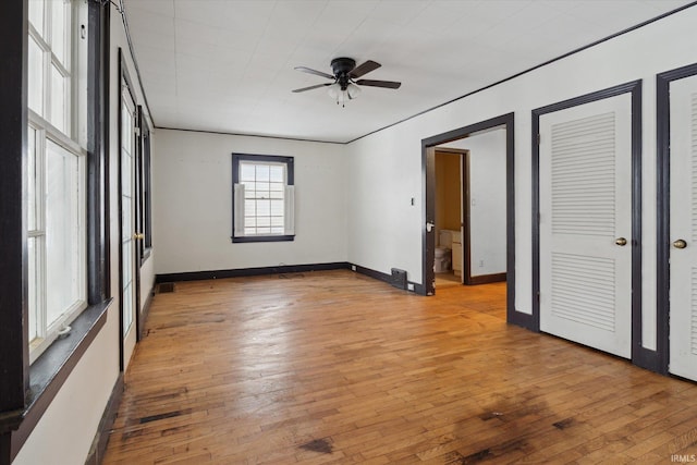 unfurnished bedroom with ceiling fan, light hardwood / wood-style floors, and multiple closets