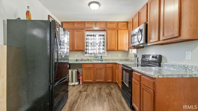 kitchen featuring sink, black appliances, and light wood-type flooring