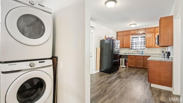 laundry room featuring dark wood-type flooring, sink, and stacked washer and clothes dryer