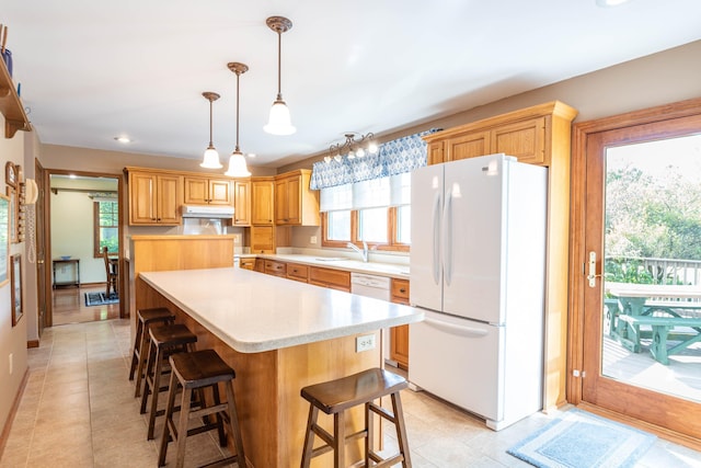 kitchen with a wealth of natural light, pendant lighting, white fridge, and a kitchen island