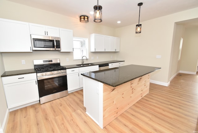 kitchen with white cabinetry, sink, a center island, hanging light fixtures, and appliances with stainless steel finishes