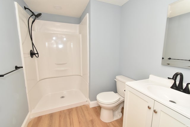 bathroom with hardwood / wood-style flooring, vanity, toilet, and a shower