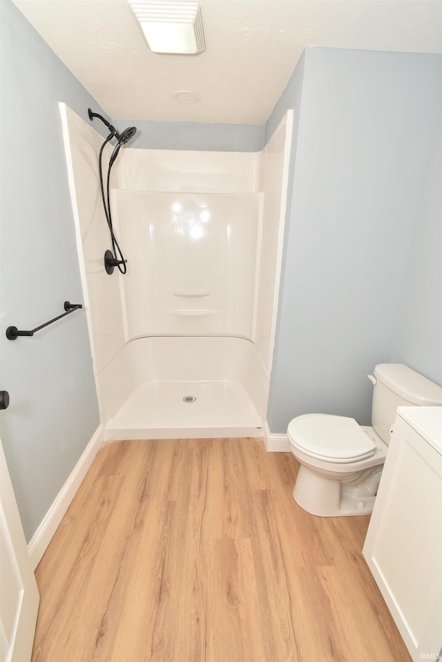 bathroom with a shower, hardwood / wood-style floors, and toilet