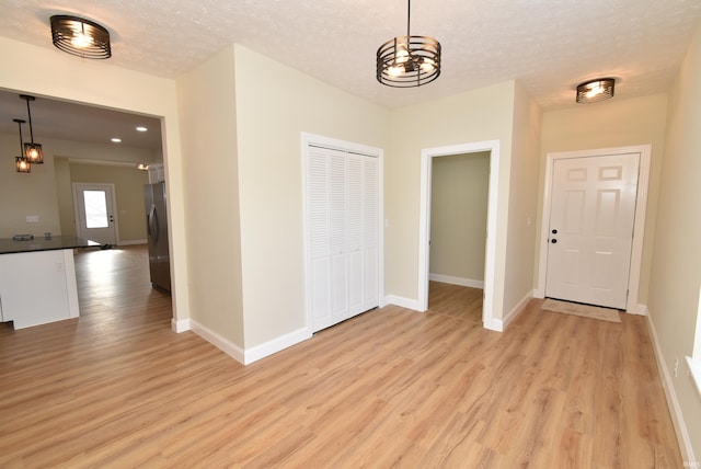 entrance foyer with an inviting chandelier, a textured ceiling, and light wood-type flooring