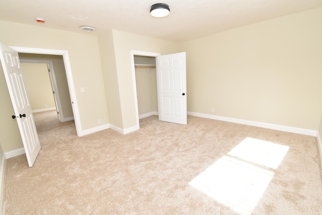 unfurnished bedroom featuring a closet and light colored carpet